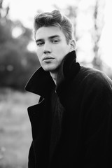 Portrait of a man with dark hair. A man in a black coat in the field