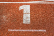 Startnummer eins auf Aschenbahn von Leichtathletik-Laufbahn
