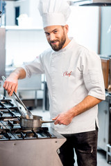 Portrait of chef cook in uniform with knifes at the restaurant kitchen