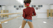 © Dash - Woman in shorts and checkered top poses in studio before a mirrored wall