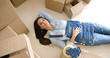 © Dash - Attractive young woman relaxing on her back on the floor surrounded by brown cardboard cartons as she packs up the house for a move or renovation.