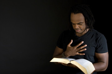 Man reading a bible isolated on black.