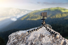Closeup of action camera on flexible tripod, standing on the roc