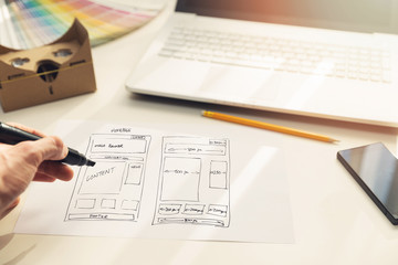 Wall Mural - designer drawing website development wireframe on paper in office