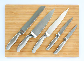 Set of professional kitchen knives on a wood board, top view