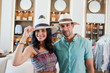 © phocal Media - Expat couple trying on hat at boutique.