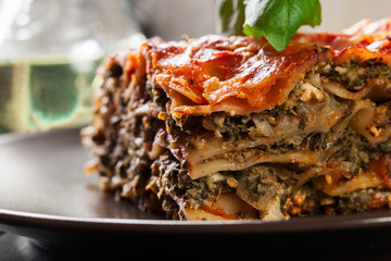 Wall Mural - Piece of tasty hot lasagna with spinach on a plate