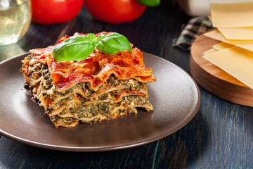 Wall Mural - Piece of tasty hot lasagna with spinach on a plate