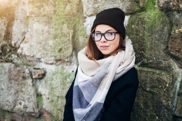 Wall Mural - Beautiful girl with blue eyes in black glasses in hat and coat with scarf in the winter park