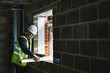 © Mint Images - Construction worker sawing piece of wood at construction site