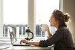 © Cavan Images - Side view of young woman using laptop
