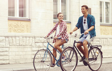 Young Couple Of Hipsters Riding A Bicycle. Date In Old Town. Love, Relationship, Romance Concept.
