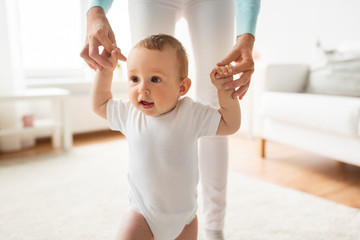 happy baby learning to walk with mother help