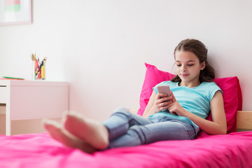 Wall Mural - smiling girl texting on smartphone at home