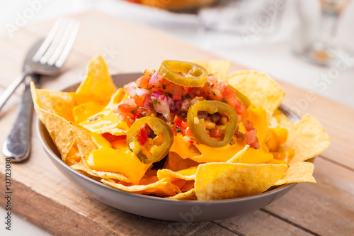 Fotografía Spicy nachos with chopped onions and tomatoes, jalapeno slices and melted cheese