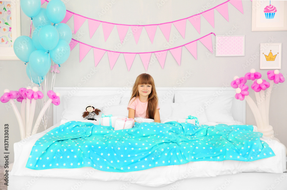 Cute birthday girl in bed with giftboxes