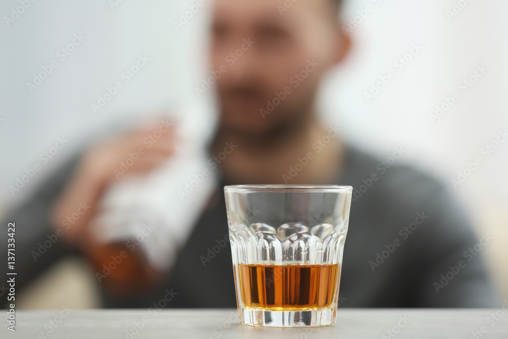 Glass with whisky on table against blurred background