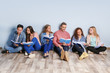 © Africa Studio - Group of people with books sitting on floor near light wall