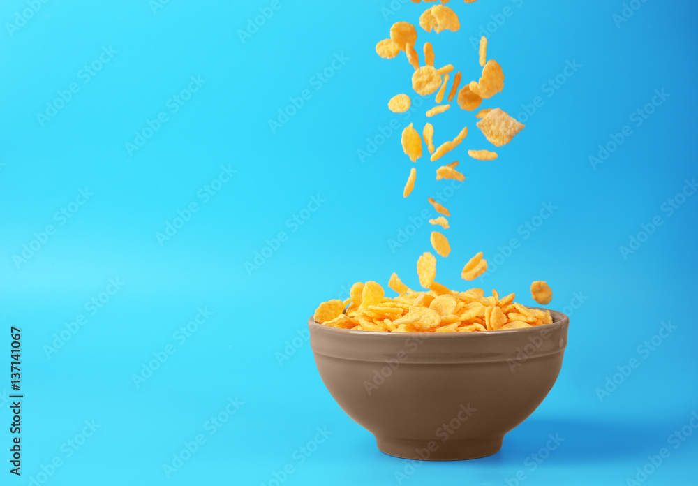 Bowl with corn flakes on blue background