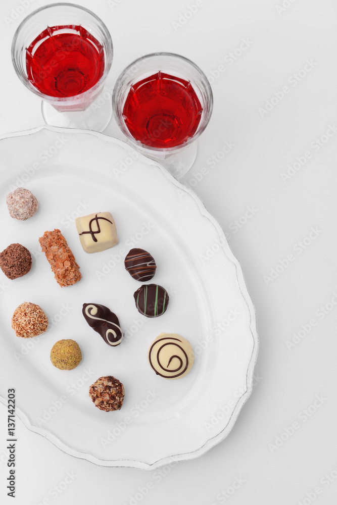 Delicious chocolate candies and wine on white background