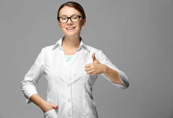 Wall Mural - Young woman with spectacles on grey background