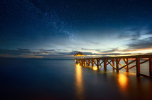 Beautiful Night Seascape With Milky Way In The Sky And Pier Stretching Into The Ocean.
