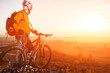 © Aleksey - low angle view of cyclist standing with mountain bike on trail at sunset