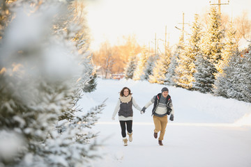 happy loving couple walking in snowy winter forest, spending christmas vacation together.