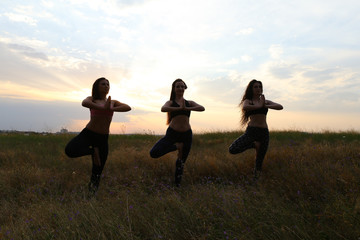 Energetic girls standing on one leg and kept bent at elbows in f