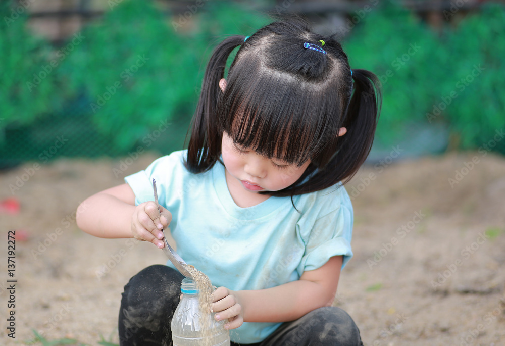 Cute little girl playing in garden with soil Stock Photo | Adobe Stock