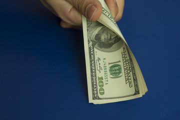 Man's hands holding dollars on dark blue background