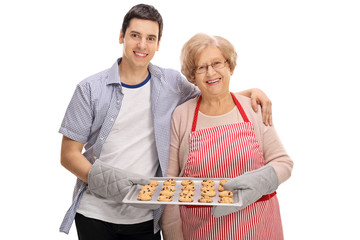 Poster - Cheerful young man and elderly lady holding tray of cookies