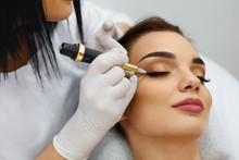 Beautician Doing Eyebrow Makeup Tattoo On Woman Using Machine