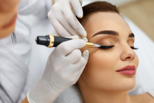 Beautician Doing Eyebrow Makeup Tattoo On Woman Using Machine