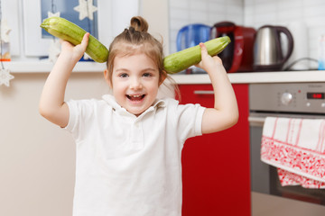 Little kid with two zucchini