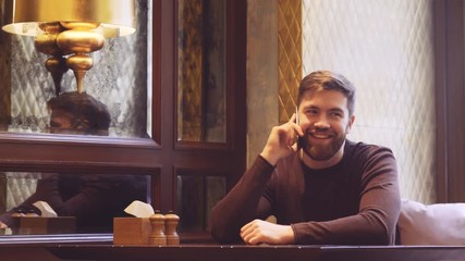 Sticker - Smiling Bearded Man sitting in cafe by the table and talking on phone