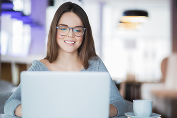 Smiling young Caucasian woman working at laptop