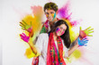 Indian Couple playing colours or people celebrating holi, with holding mobile or white board or pichkari or sweets, isolated over white background