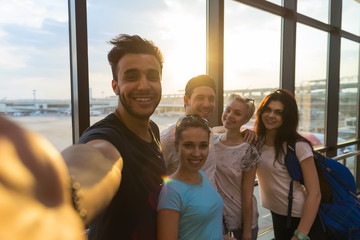 Wall Mural - young people group in airport lounge near windows happy smile mix race friends taking selfie photo f