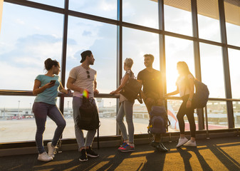 Wall Mural - young people group in airport lounge near windows waiting departure speaking happy smile mix race fr