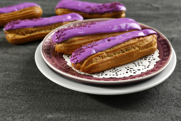 Sticker - Plate with delicious glazed eclairs on dark textured background