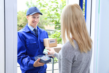 Wall Mural - Young woman paying for package from courier