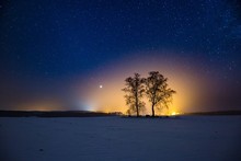 Milky Way And Starry Sky Over Winter Landscape And Distant Village