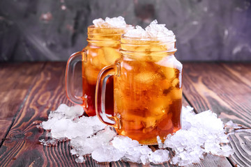 Two glass jars with iced tea on rustic background Copy space