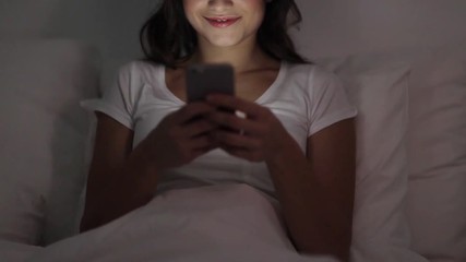 Canvas Print - happy young woman with smartphone in bed at night