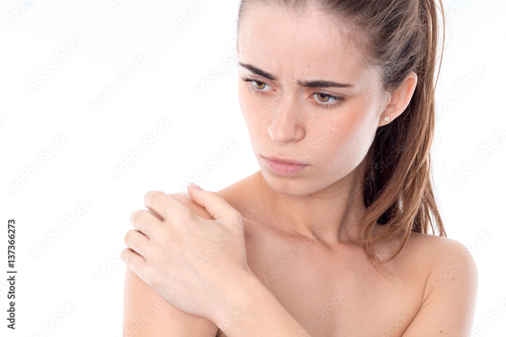 nude young girl stares into the distance and keeps hand on the shoulder