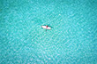 Luftaufnahme einer Frau auf einem Stand Up Paddle über türkisem Wasser