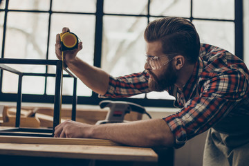 Closeup side view photo of handsome  worker with ruler. Stylish young entrepreneur with brutal hairstyle and saved glasses work at his workplace. He love his job