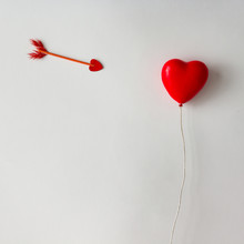 Red Heart Shaped Balloon With Cupid Arrow On White Background. Love Concept. Flat Lay.