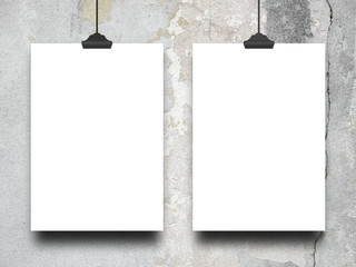 Two blank frames hanged by clips against cracked wall